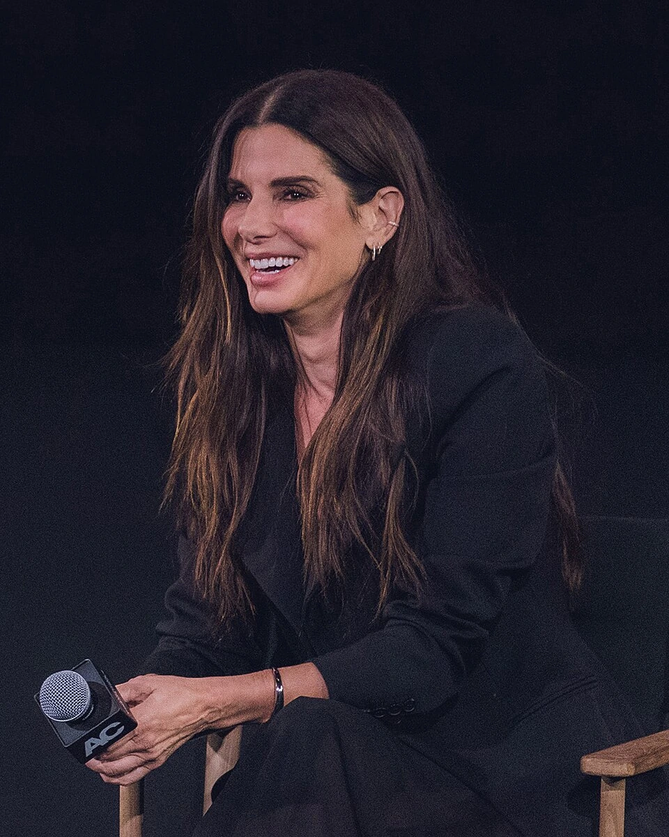 Sandra Bullock smiling while seated and holding a microphone at The Egyptian Theatre, 2024.