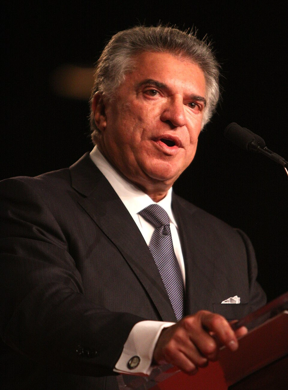 Al Cárdenas speaking at a podium in a formal setting