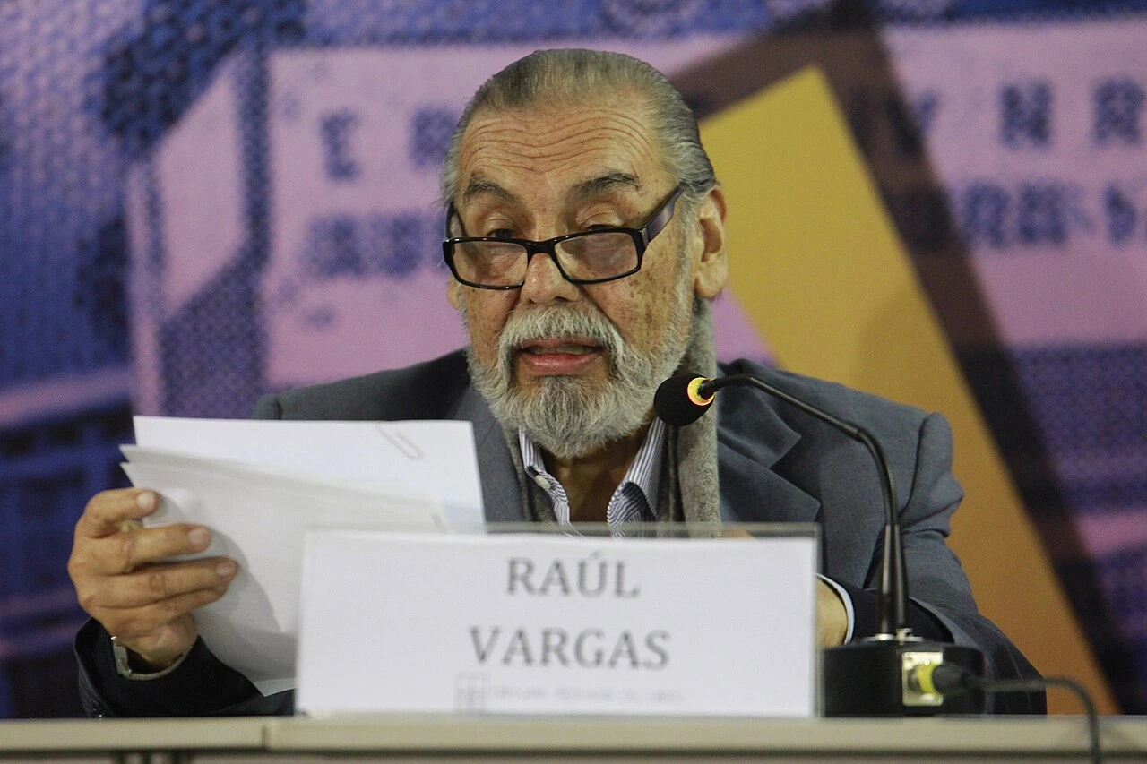 Raúl Vargas speaking at a microphone during a formal event