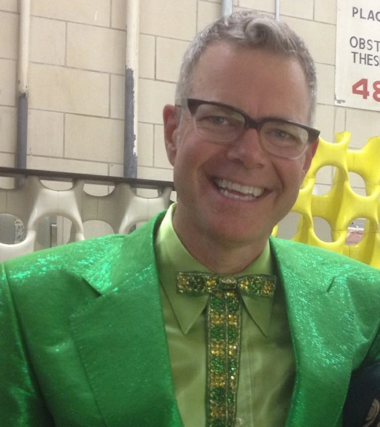 Charles Phoenix smiling in a bright green suit and bow tie