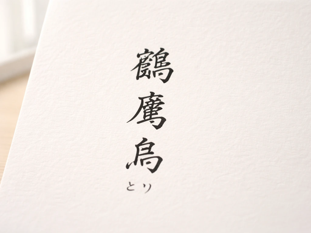 Close-up of three bird kanji characters with small kana readings beneath on a plain desk.