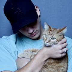 A man in a black cap holding an orange tabby cat
