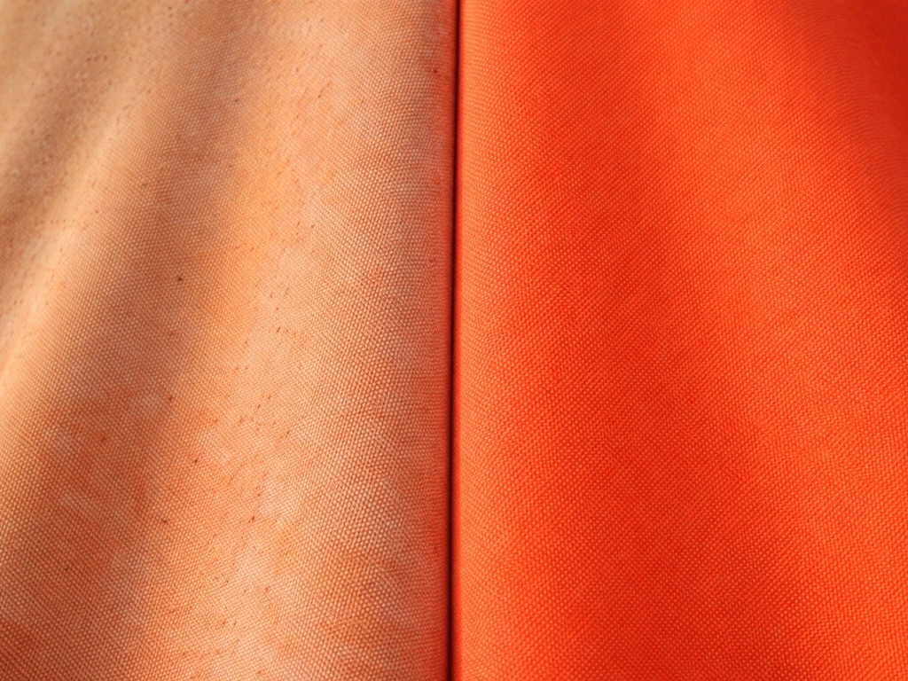 Closeup of polyester umbrella fabric showing UV-faded worn panel beside a fresher panel.