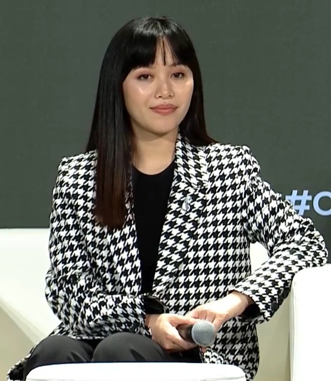 Michelle Phan speaking onstage at an event, seated with a microphone in hand.