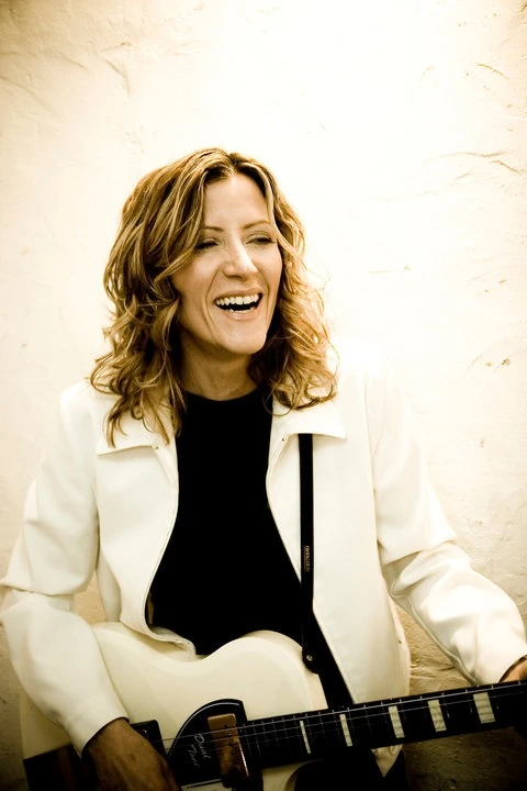 Michelle Malone smiling while holding a guitar