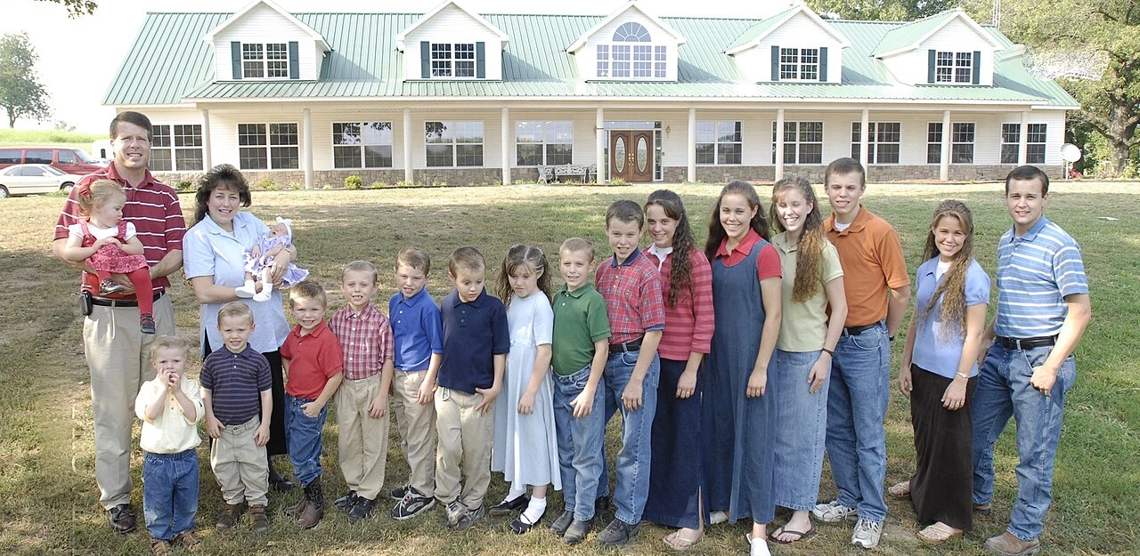 Duggar family posed outdoors in front of a large house