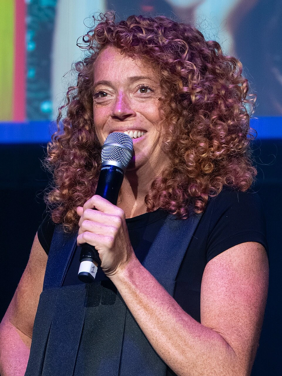 Michelle Wolf holding a microphone on stage