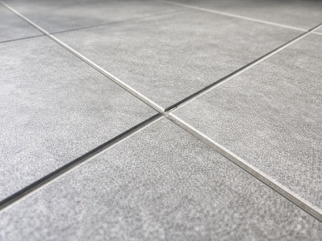 Close-up of a porcelain tile patio surface with grout lines, showing texture in natural light.