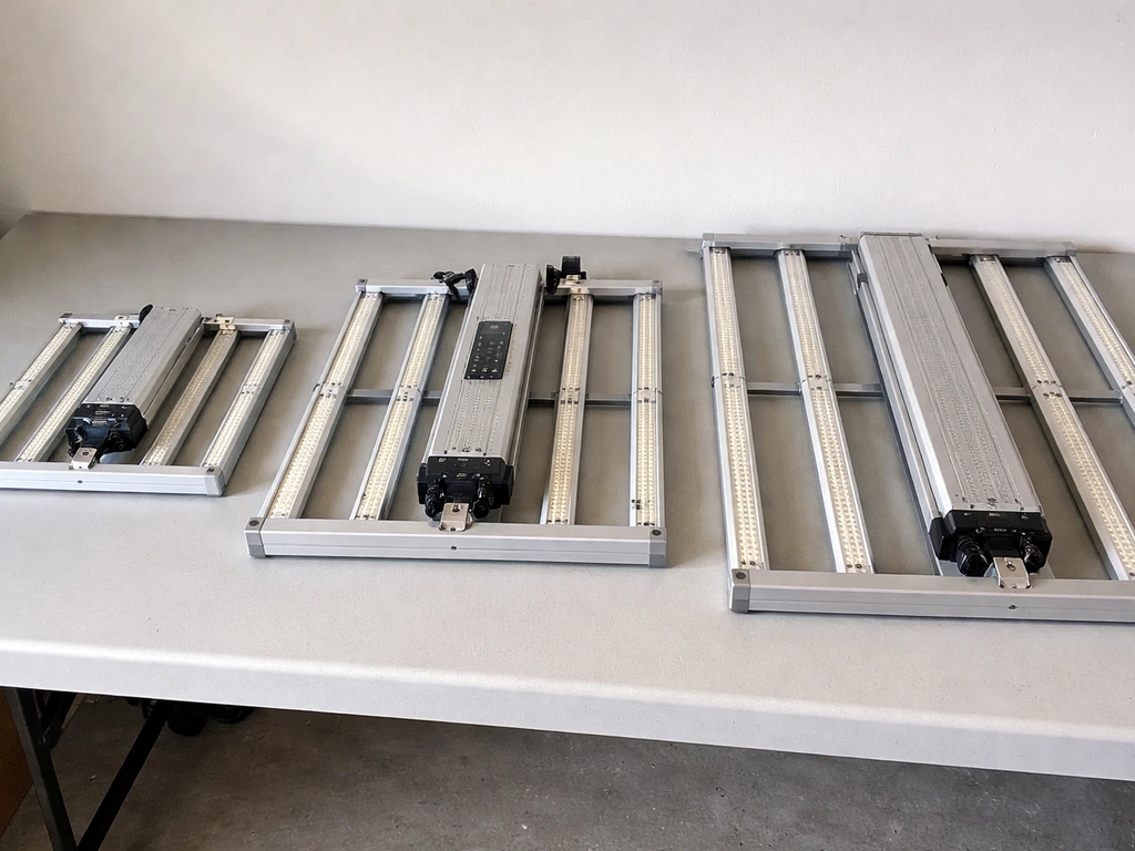Three different grow light fixtures placed side-by-side on a workbench for a quick comparison.