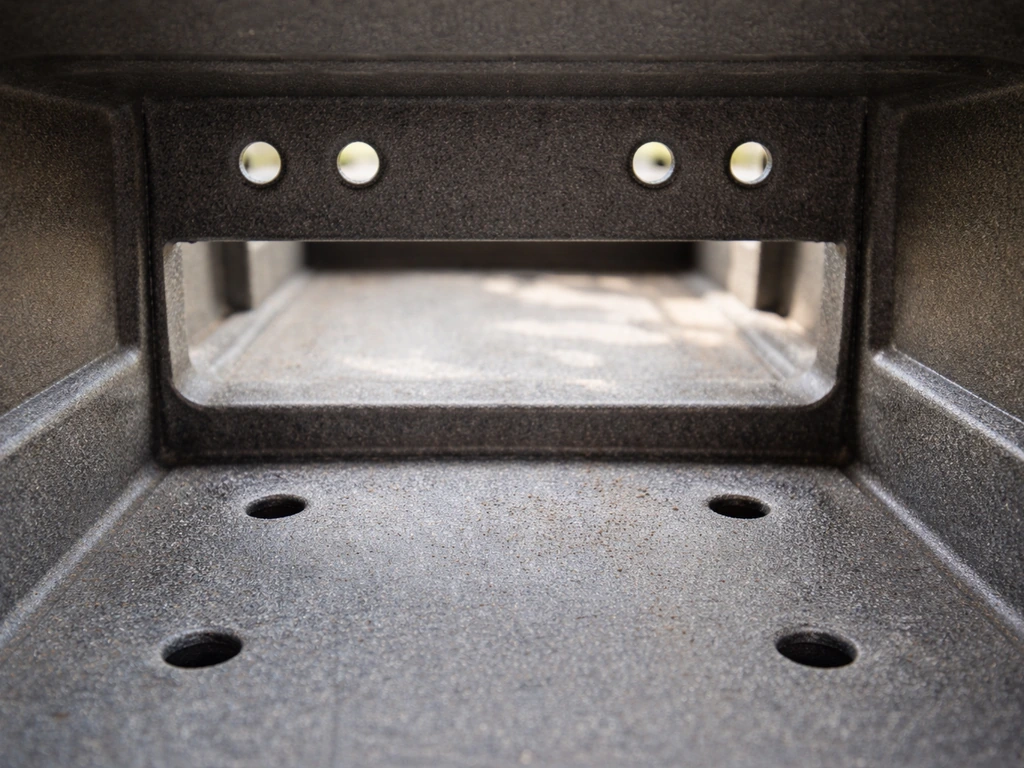 Close-up of upper side-wall ventilation holes and floor drainage holes inside an outdoor enclosure.
