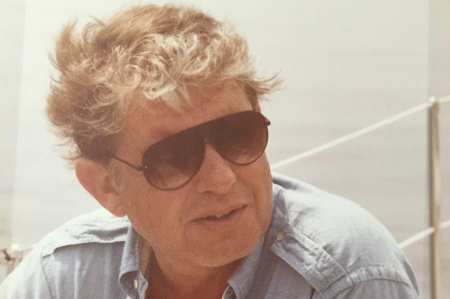 Portrait of an older man with curly hair and sunglasses, likely a business executive or founder.