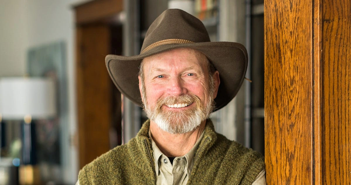 Portrait of Ward Schraeder smiling in a cowboy hat indoors.