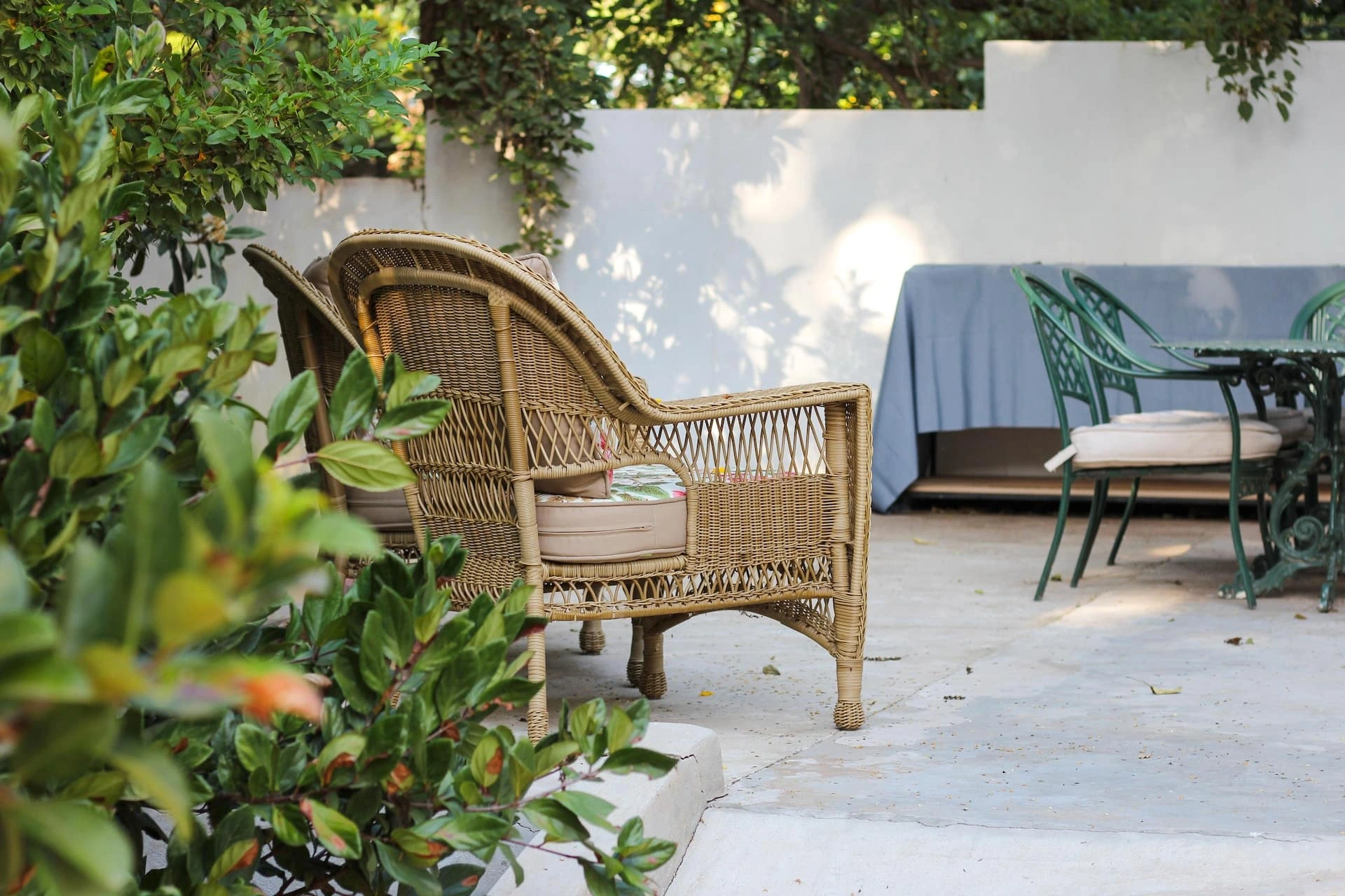 Outdoor patio furniture set with wicker chairs and dining table in a garden setting