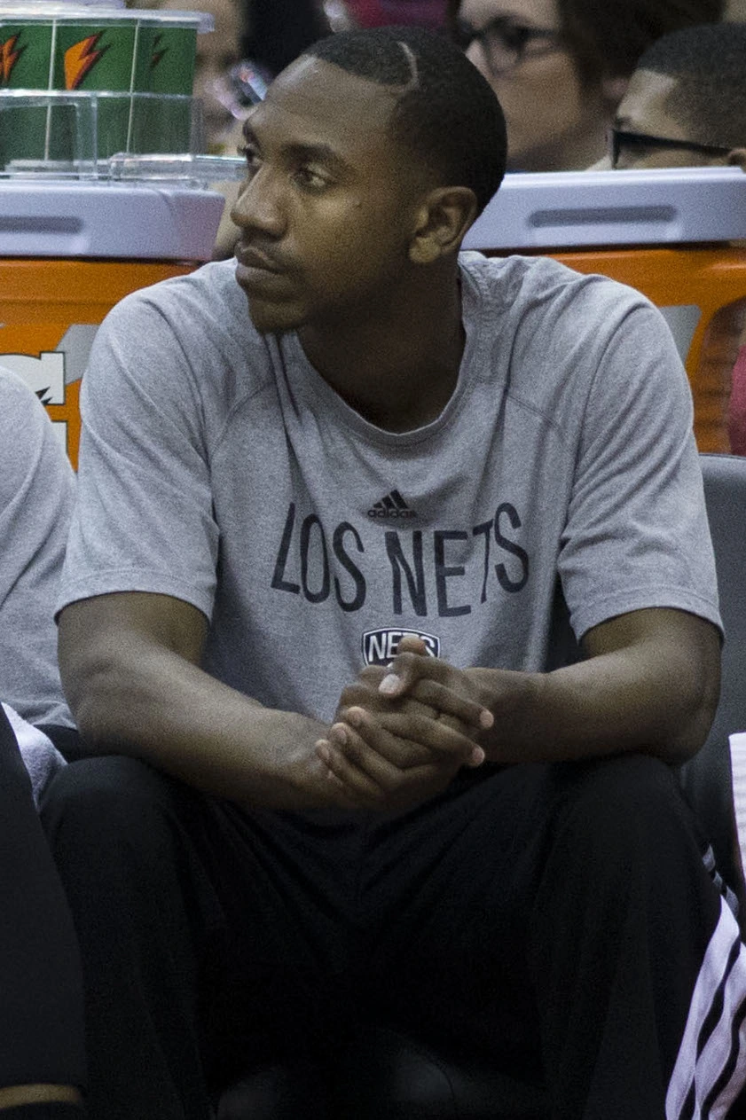 Marquis Teague seated in a gray Los Nets shirt at a basketball event, looking to the side.