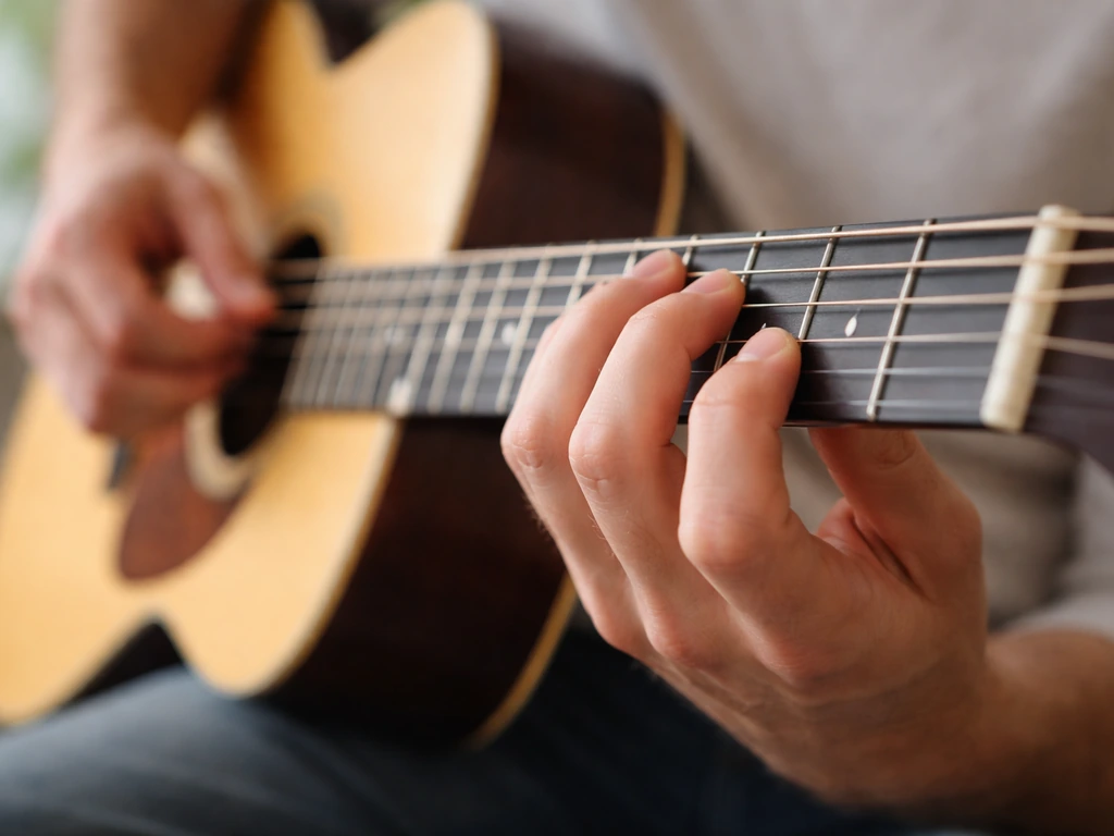 Close-up of a guitarist’s hands fretting nearby frets on a guitar to show short, singable phrases.