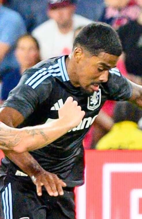 Ian Maatsen in action during a match, wearing a dark Aston Villa kit.