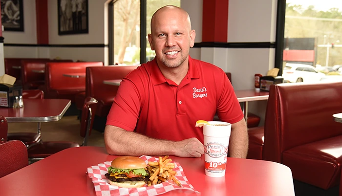 David Alan Bubbus Jr. seated inside a David's Burgers restaurant
