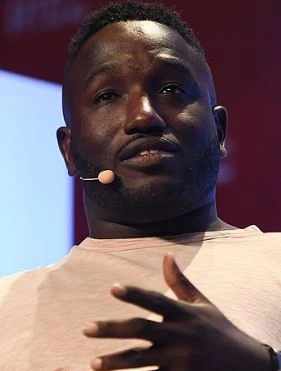 Hannibal Buress speaking on stage with a headset microphone