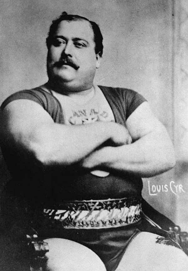 Black-and-white portrait photo of Louis Cyr, the Canadian strongman, seated with arms crossed.
