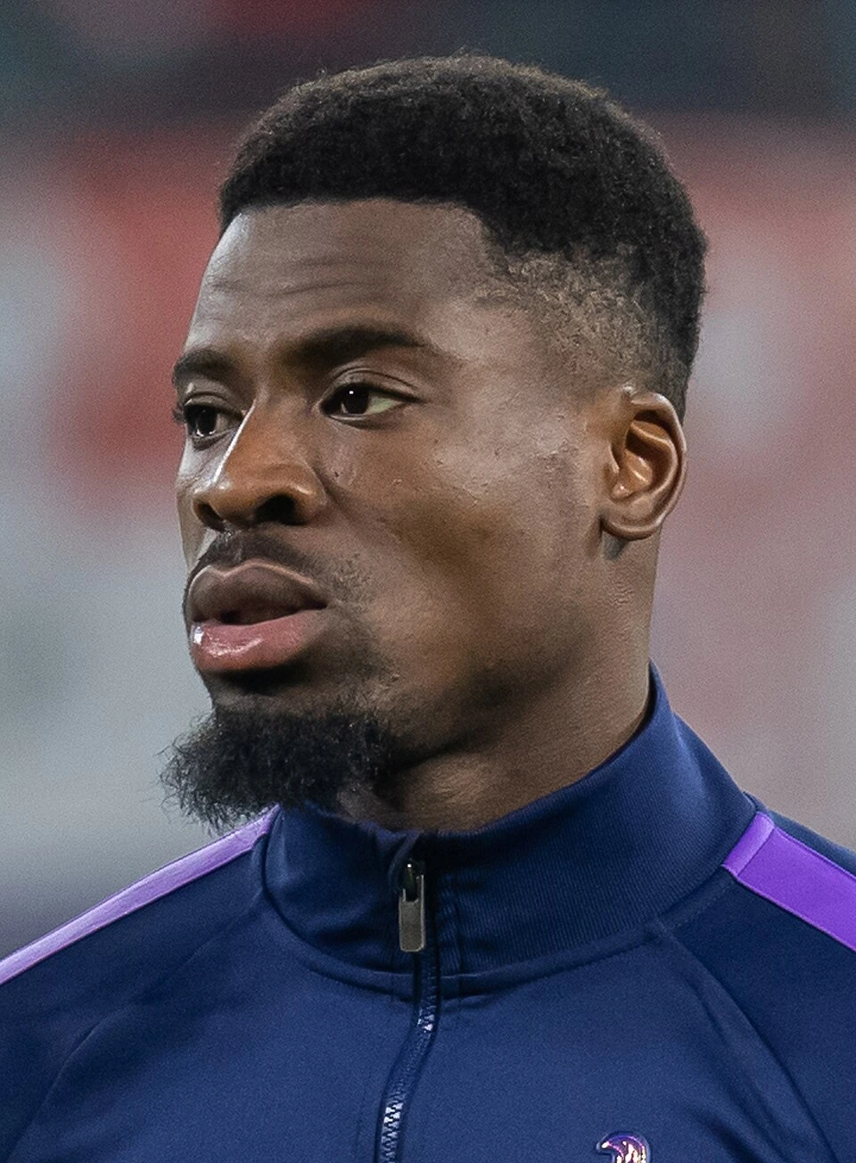 Serge Aurier in a pre-match close-up wearing a navy training top with purple accents.