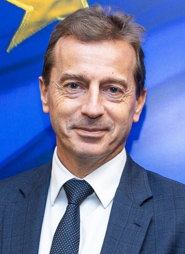 Portrait of Guillaume Faury in a suit and tie against a blue Airbus-themed background