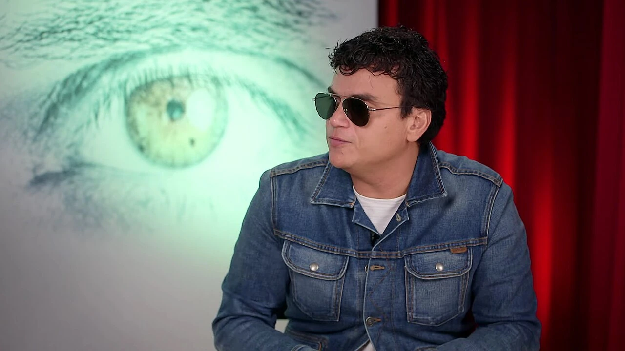 Silvestre Dangond wearing sunglasses and a denim jacket in an interview setting