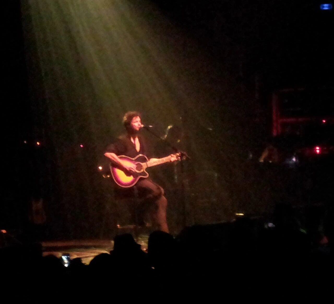Bertrand Cantat performing onstage with a guitar under stage lighting