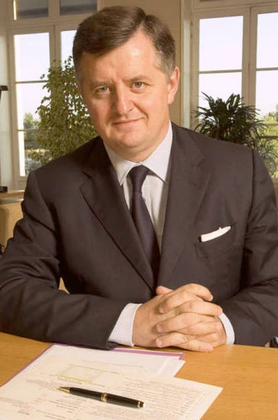 Portrait of a man in a suit seated at a desk in an office