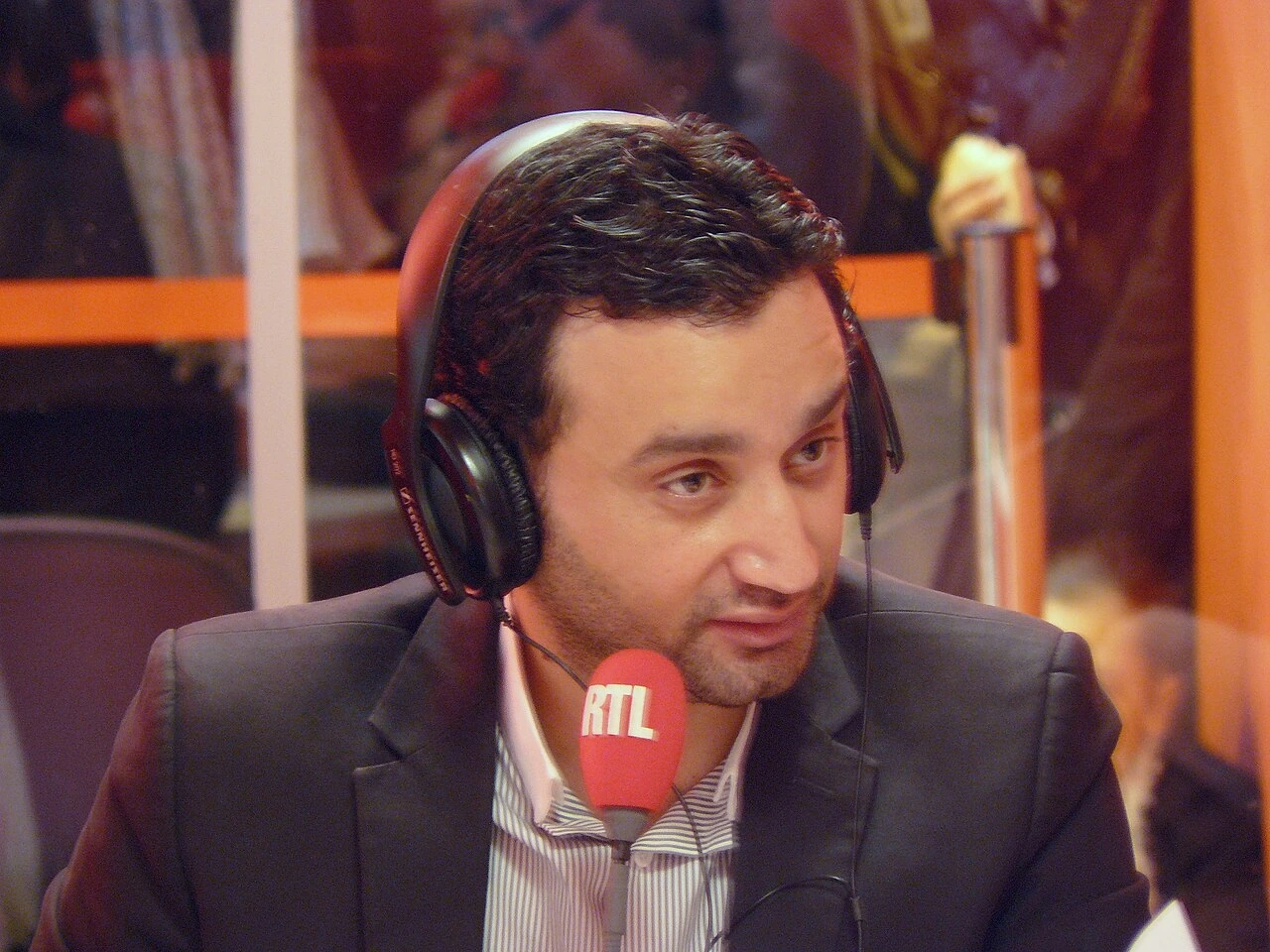Cyril Hanouna speaking into an RTL microphone while wearing headphones in a radio studio