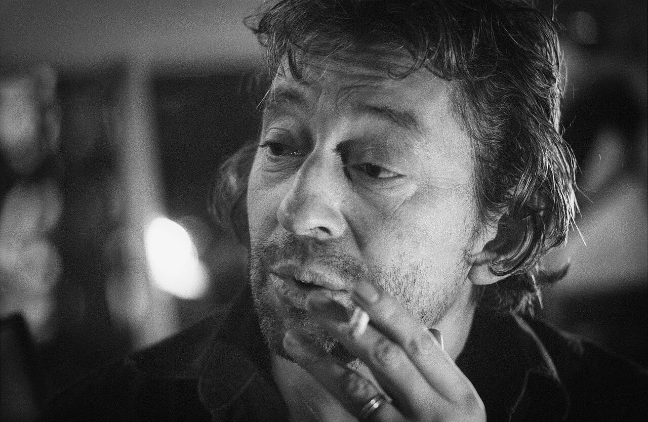 Black-and-white portrait of Serge Gainsbourg smoking a cigarette.