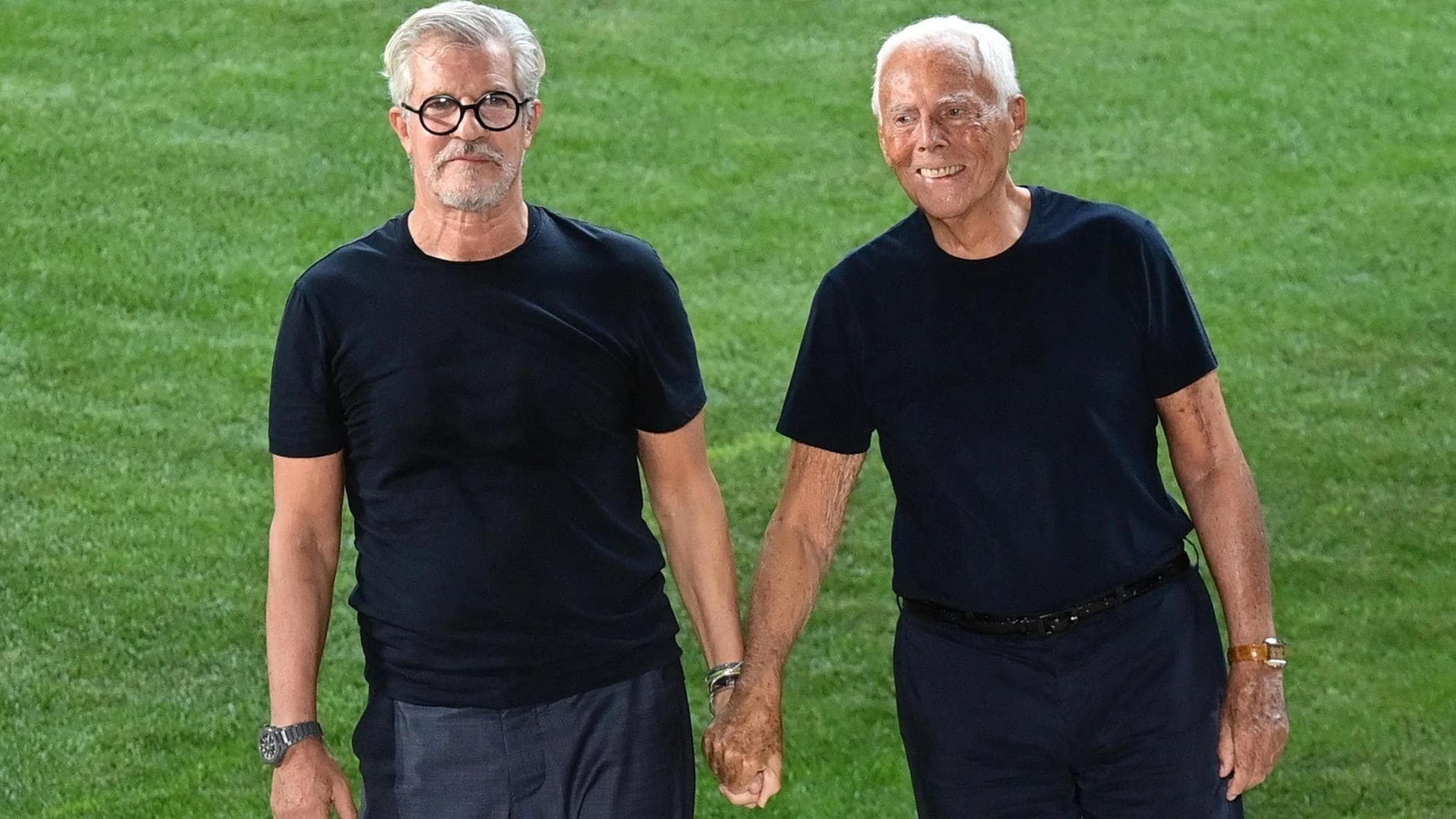 Pantaleo Dell'Orco standing outdoors beside Giorgio Armani on a green field