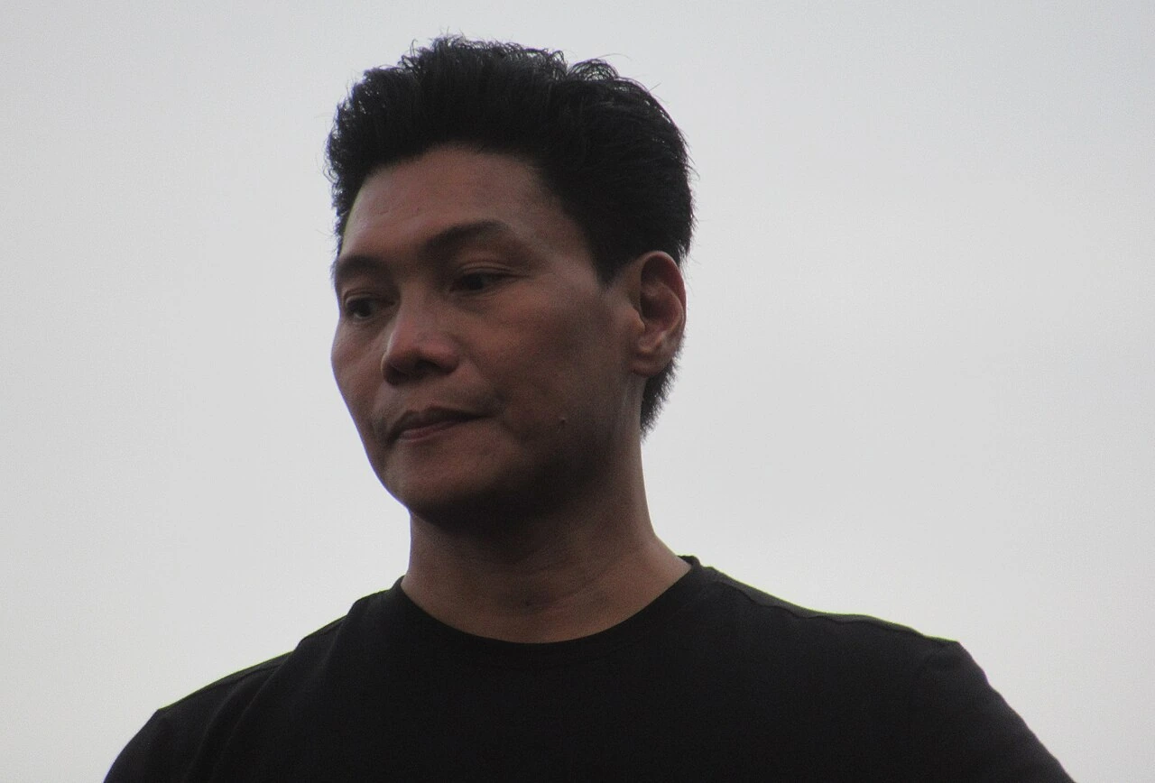 Mon Confiado standing outdoors against a bright sky