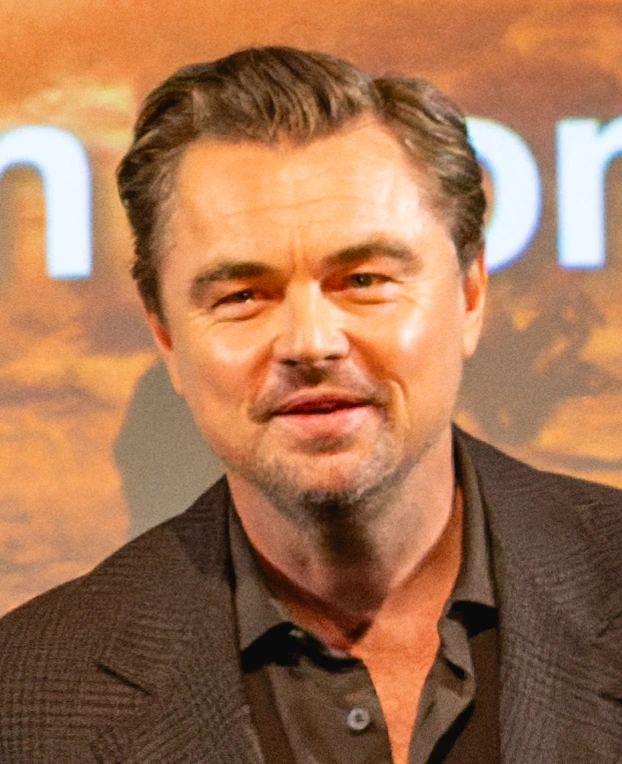 Leonardo DiCaprio at a BFI Southbank event, smiling in front of a warm-toned backdrop.