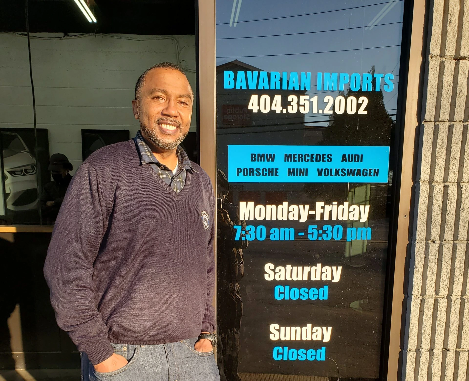 Jabari “Miles” Hayes standing outside a business storefront in casual clothes, smiling at the camera.