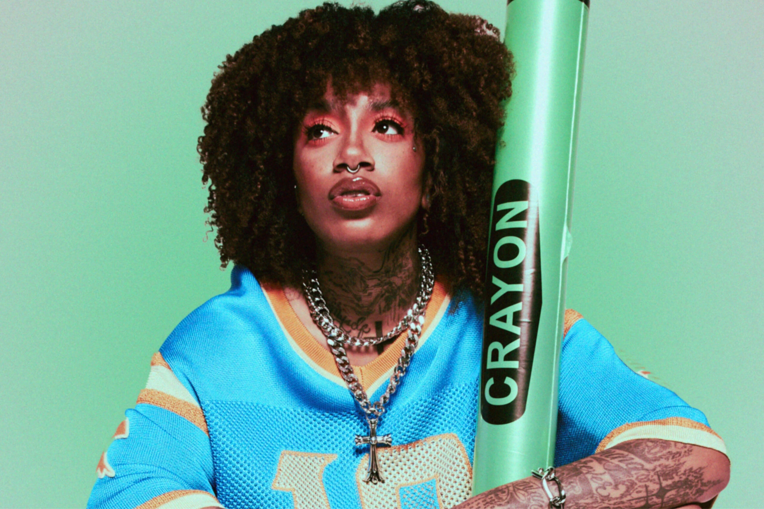 Portrait of BK the Rula holding a green prop, editorial-style photo
