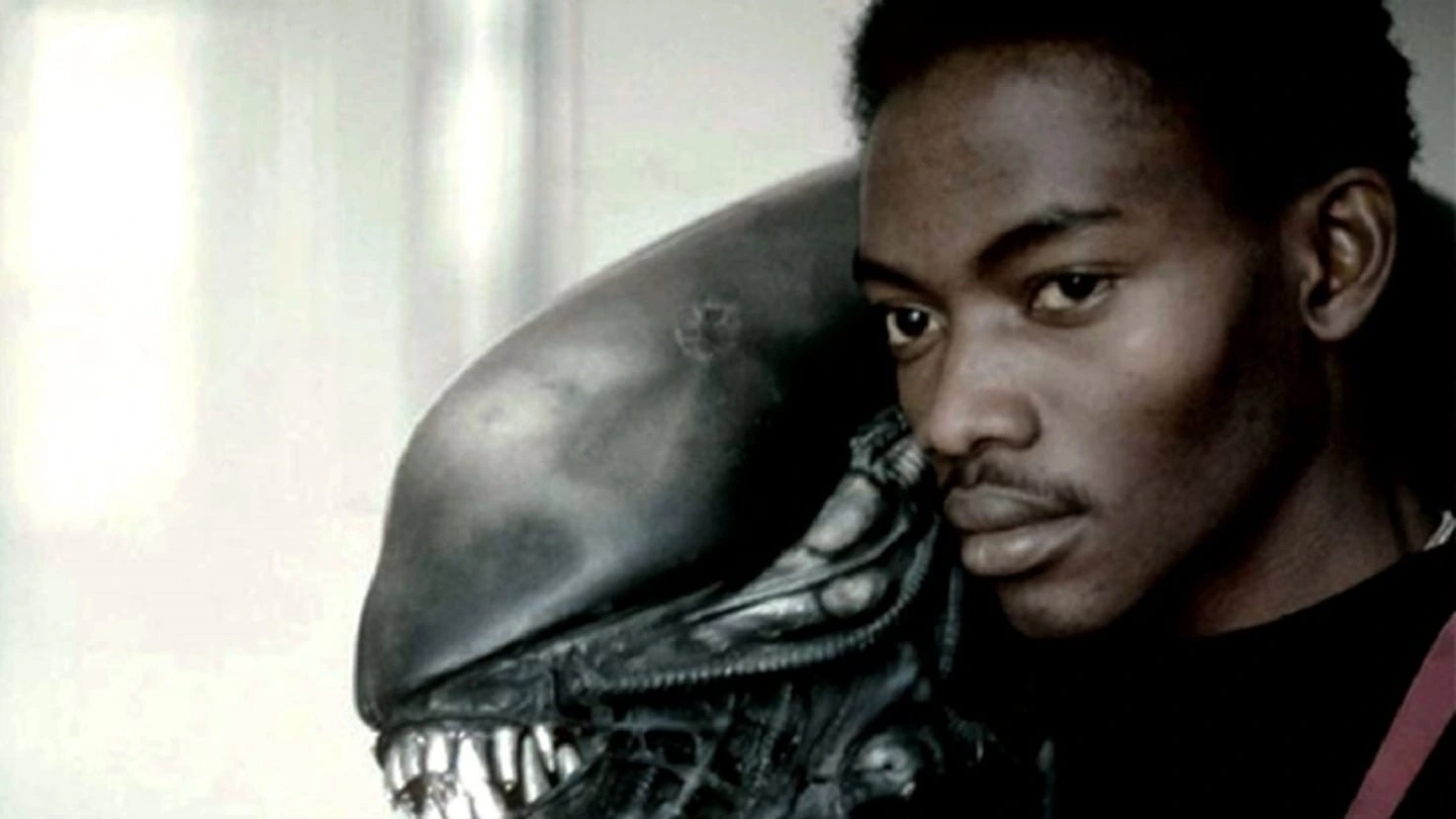 Bolaji Badejo posing beside the Alien xenomorph costume