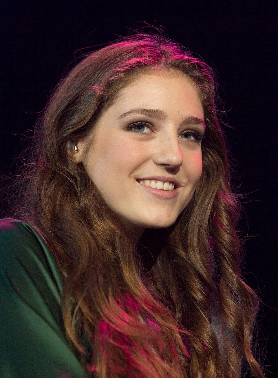 Birdy, the British singer-songwriter, smiling onstage in a concert photo