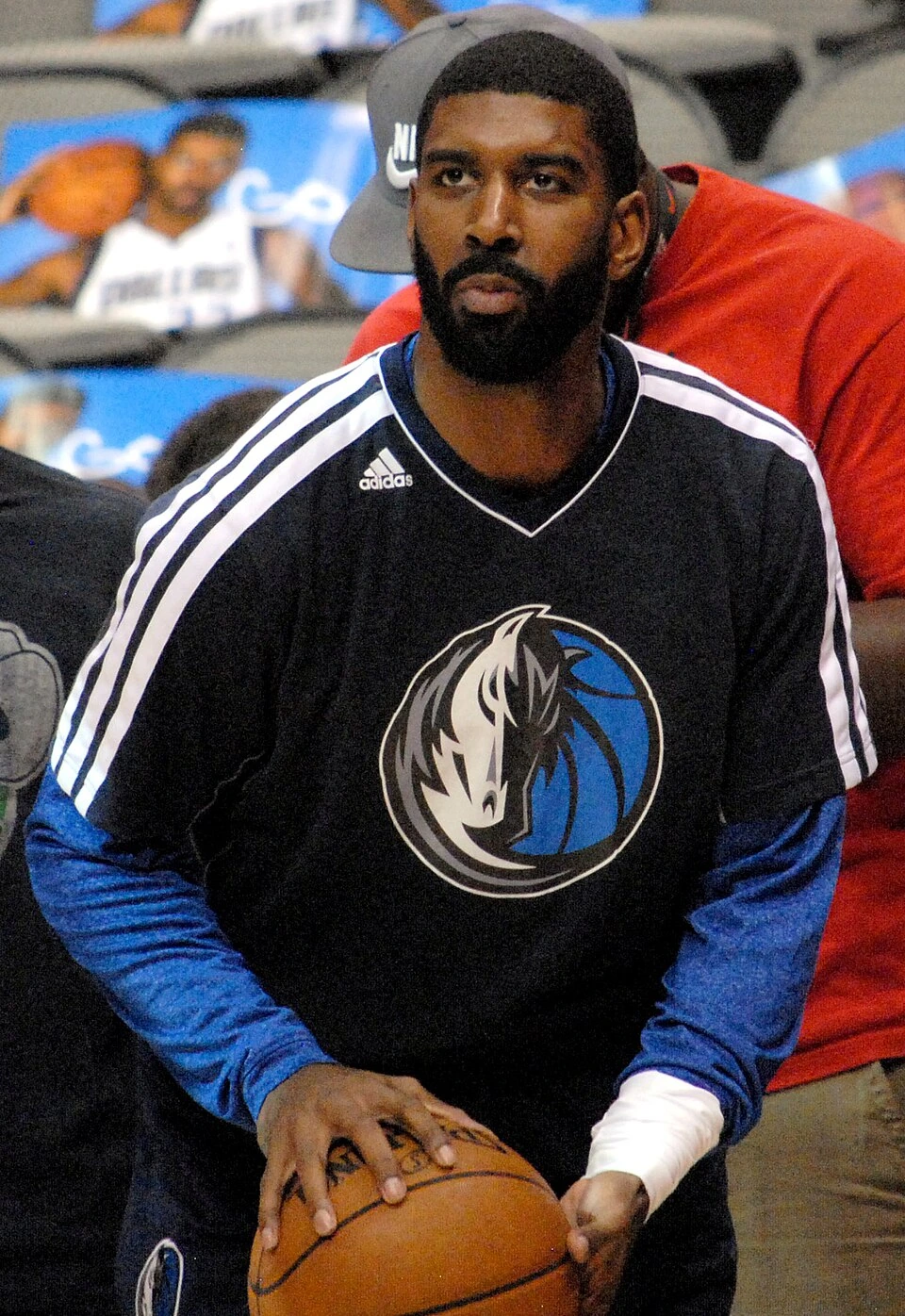 O.J. Mayo holding a basketball in a Dallas Mavericks warmup top