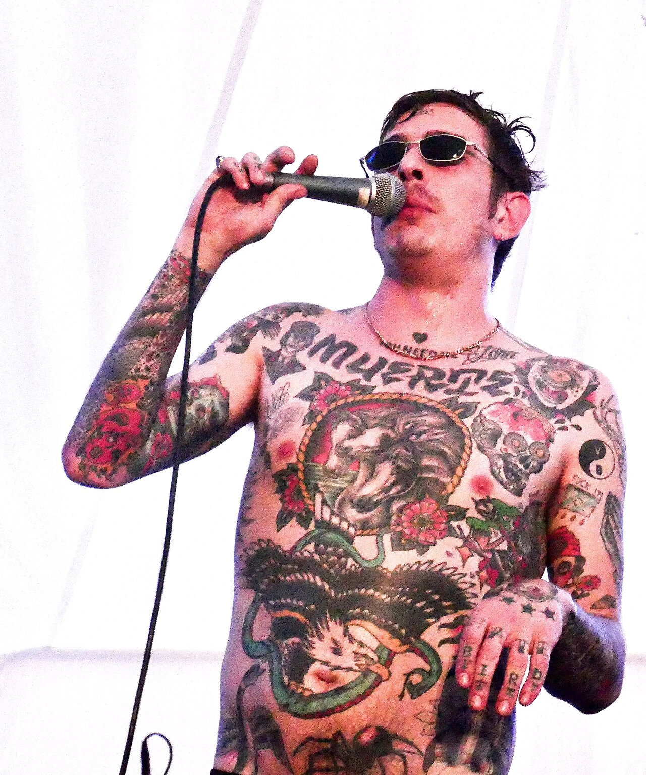 Sebastian Murphy of Viagra Boys performing on stage, shirtless and singing into a microphone.