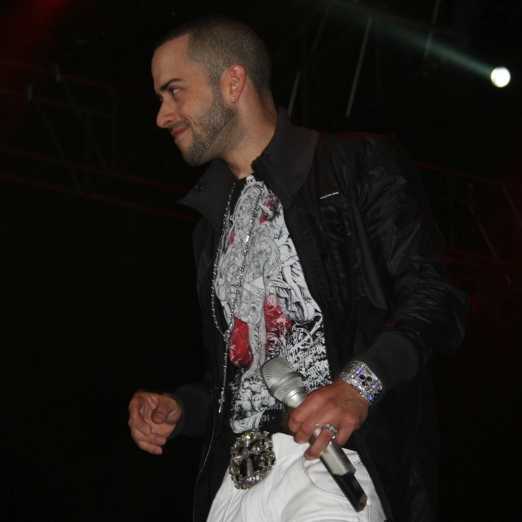 Yandel performing on stage holding a microphone