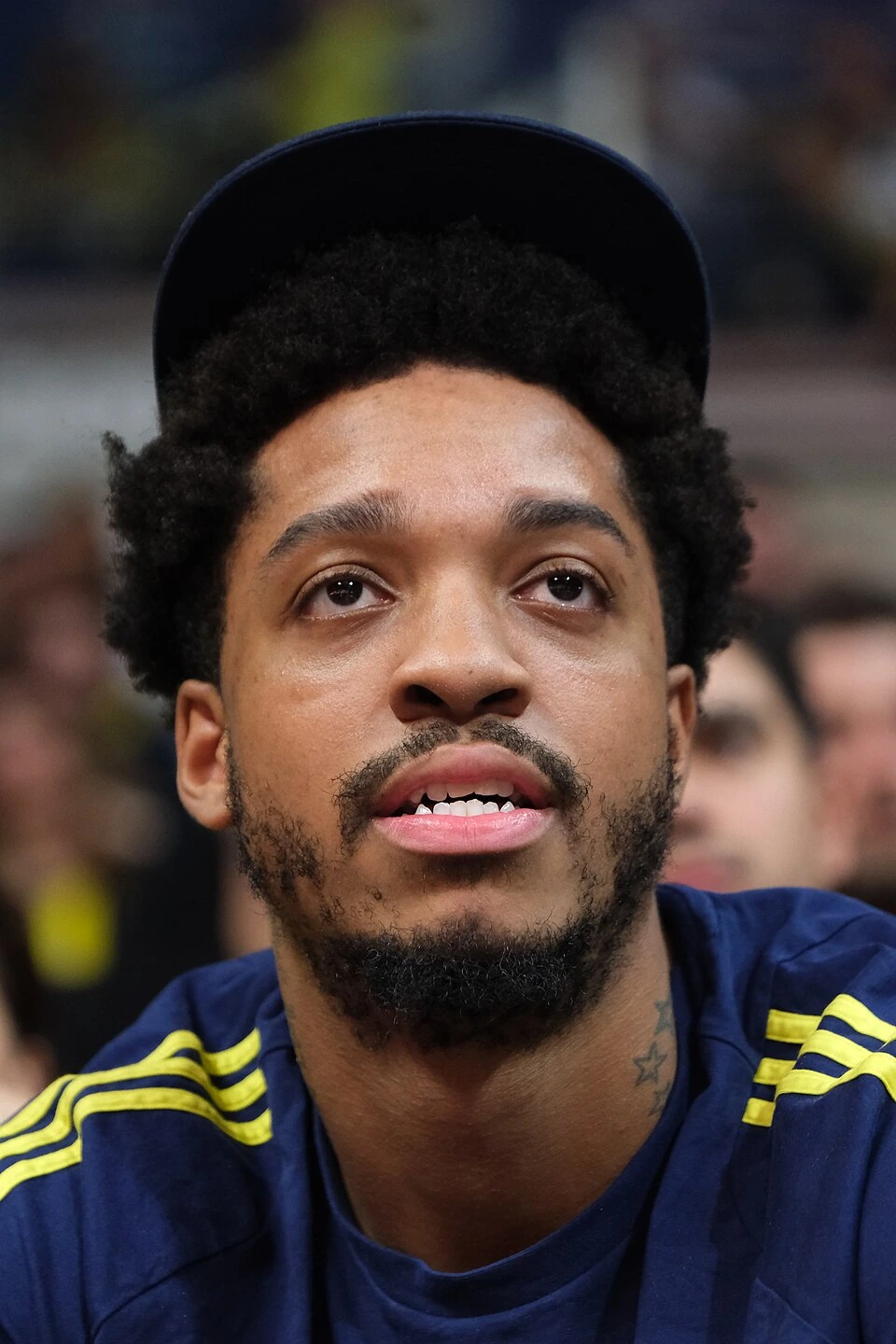 Armando Bacot in a close-up editorial-style photo wearing a navy and yellow basketball top and cap.