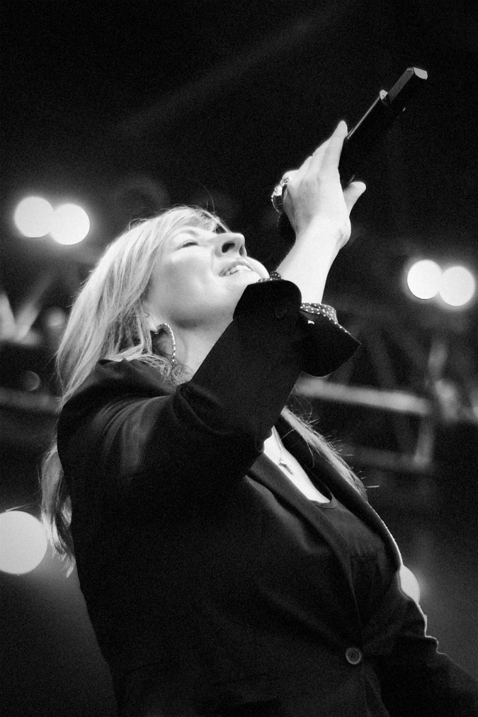 Darlene Zschech singing on stage into a handheld microphone in a black-and-white performance photo
