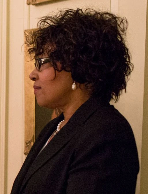 Zenani Mandela-Dlamini in profile wearing glasses and formal attire indoors