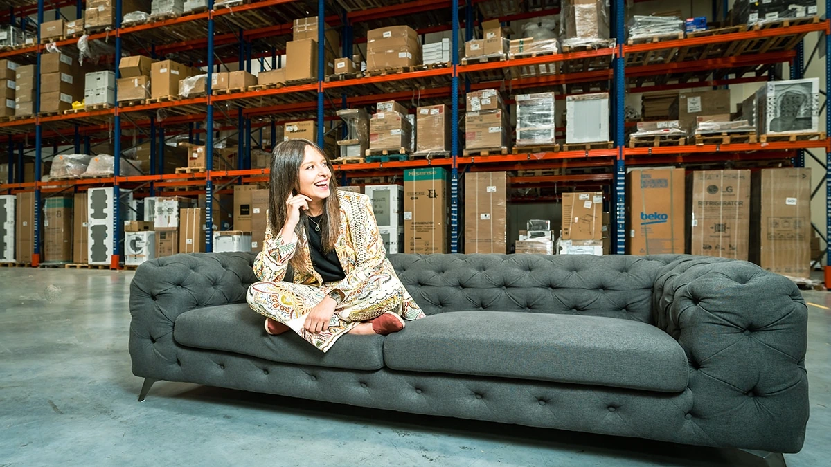 Yaiza Canosa sitting on a sofa in a warehouse, surrounded by stacked boxes