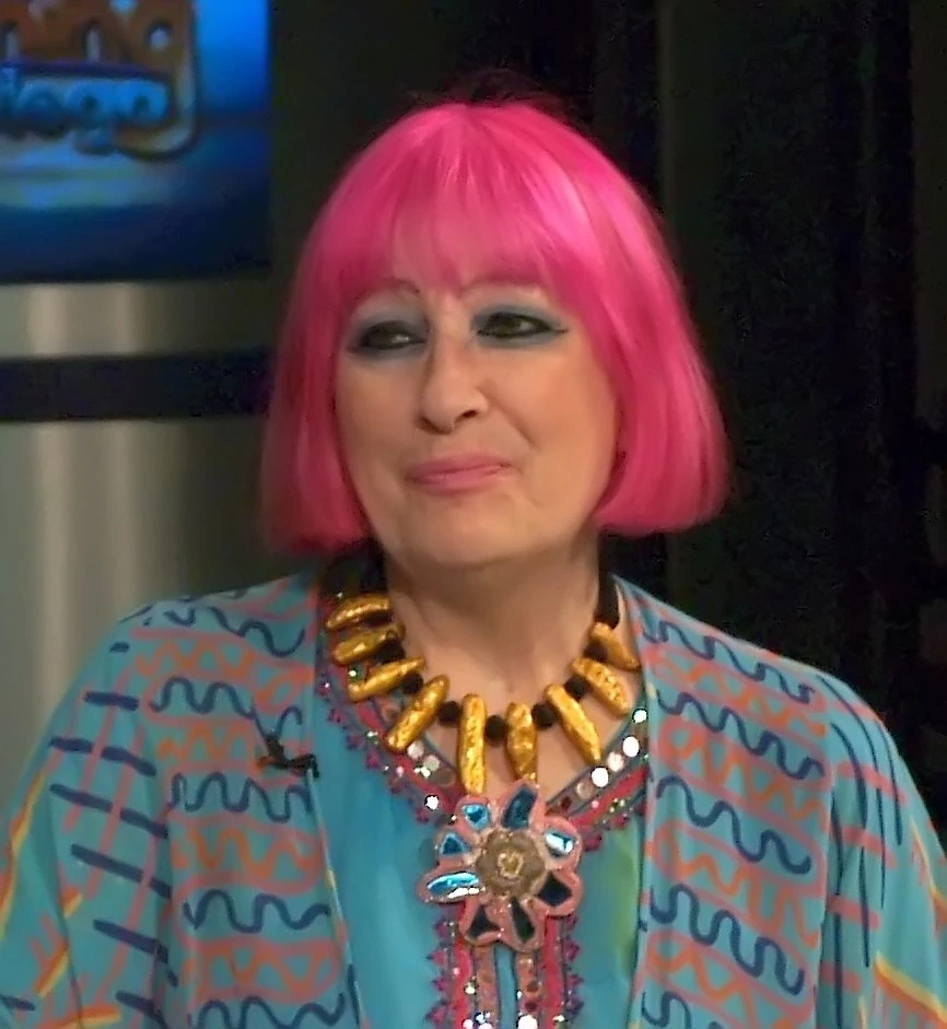 Zandra Rhodes with bright pink bob haircut and colorful patterned outfit