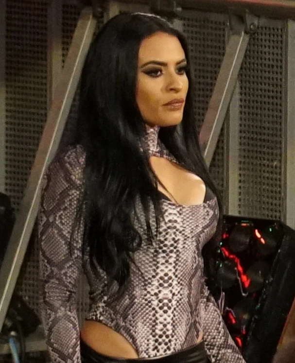Zelina Vega at a WWE event, standing in a snakeskin-patterned outfit with long black hair.