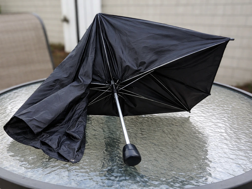 Partially opened umbrella with one side ribs not extending fully while the hub shifts.