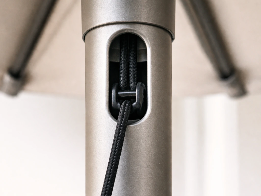Close-up of a crank umbrella pole showing a cord strap under tension through the lock seat