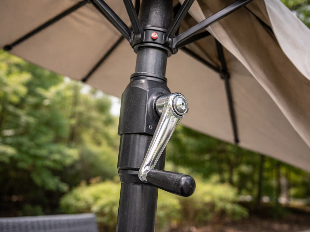 Close-up of a patio umbrella crank on the pole with the canopy partly opened, showing opening and tilt mechanism.