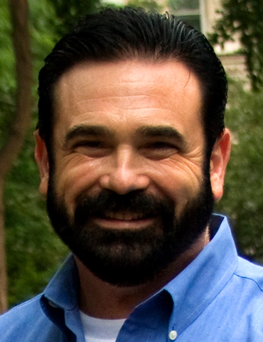 Headshot of Billy Mays smiling outdoors in a blue shirt